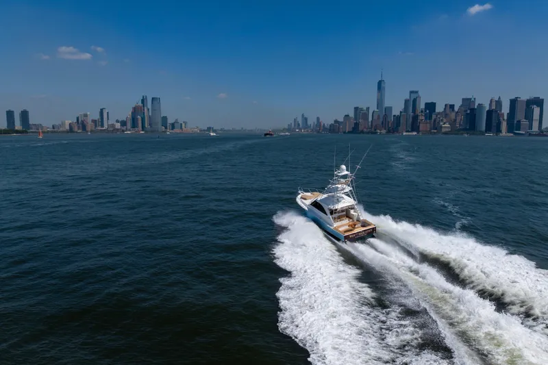  Yacht Photos Pics 2012 Cabo 44 Hardtop Express yacht cruising near city skyline on a sunny day.