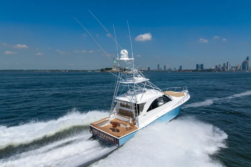  Yacht Photos Pics 2012 Cabo 44 Hardtop Express yacht cruising near city skyline on a sunny day.