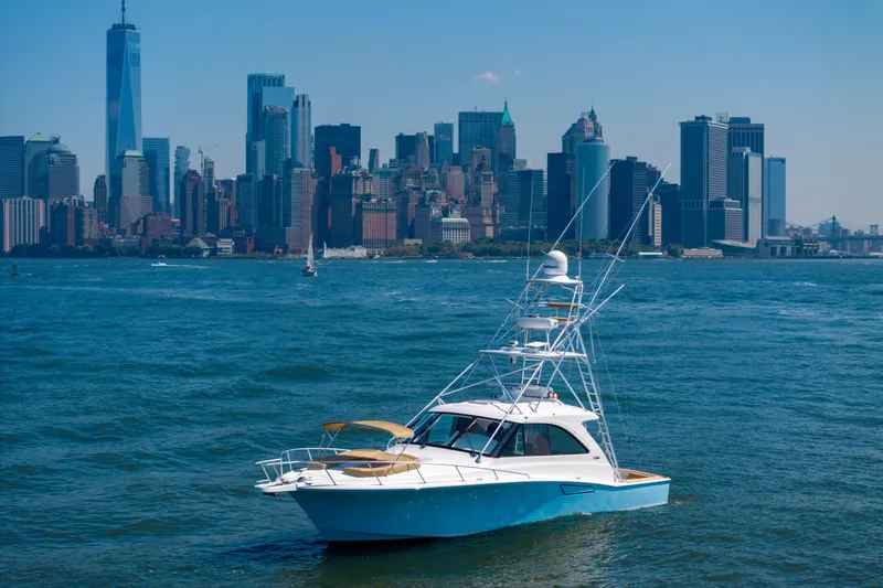  Yacht Photos Pics 2012 Cabo 44 Hardtop Express yacht in front of city skyline, clear blue sky.