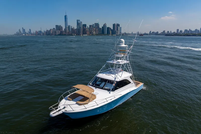  Yacht Photos Pics 2012 Cabo 44 Hardtop Express yacht cruising near city skyline on a sunny day.