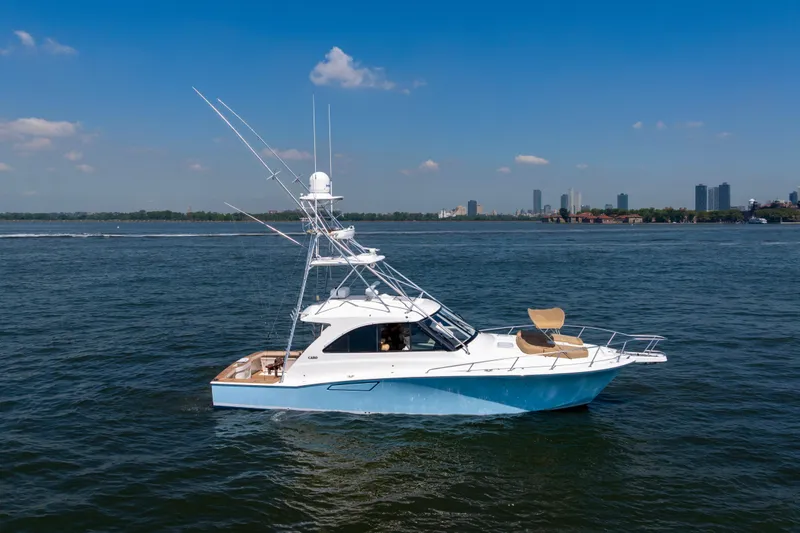  Yacht Photos Pics 2012 Cabo 44 Hardtop Express yacht on calm water with city skyline background.