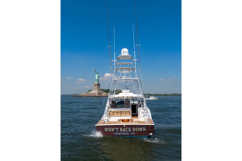  Yacht Photos Pics 2012 Cabo 44 Hardtop Express boat near Statue of Liberty, clear blue sky.