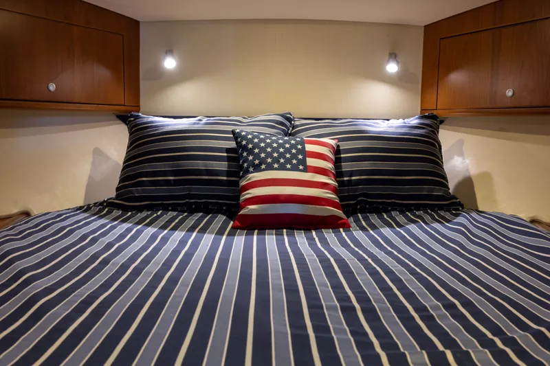  Yacht Photos Pics Cozy cabin bed in 2012 Cabo 44 Hardtop Express with striped bedding and American flag pillow.