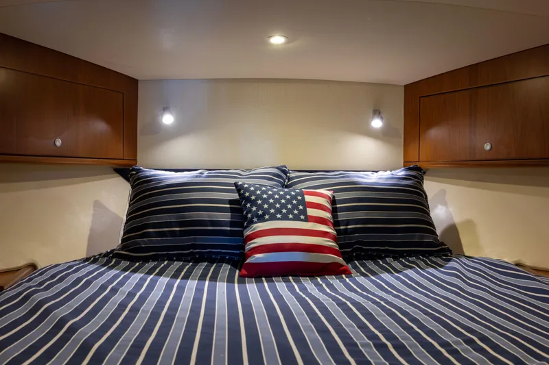  Yacht Photos Pics Cozy cabin interior of 2012 Cabo 44 Hardtop Express with striped bedding and American flag pillow.