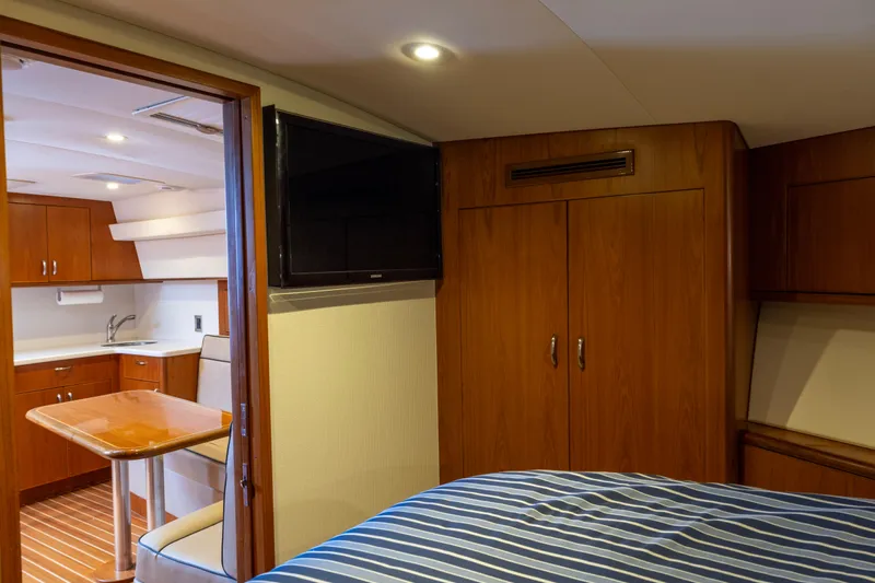  Yacht Photos Pics Interior of 2012 Cabo 44 Hardtop Express yacht with wood cabinetry and striped bedding.