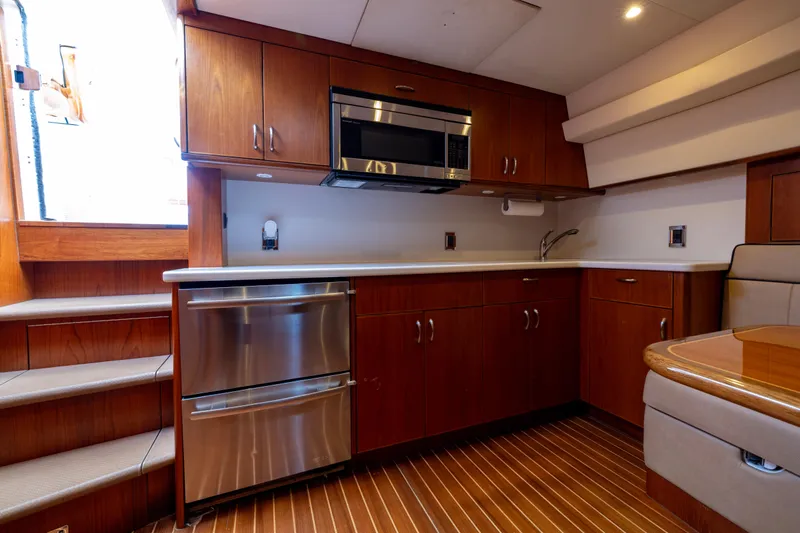  Yacht Photos Pics Luxurious 2012 Cabo 44 Hardtop Express yacht kitchen with wood cabinetry and stainless steel appliances.