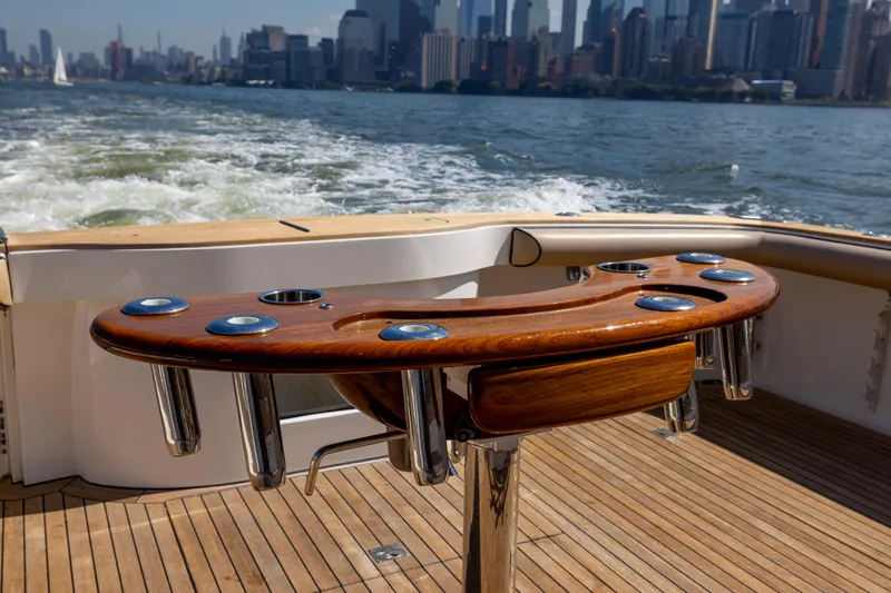  Yacht Photos Pics 2012 Cabo 44 Hardtop Express yacht with wooden deck and rod holders, city skyline in background.