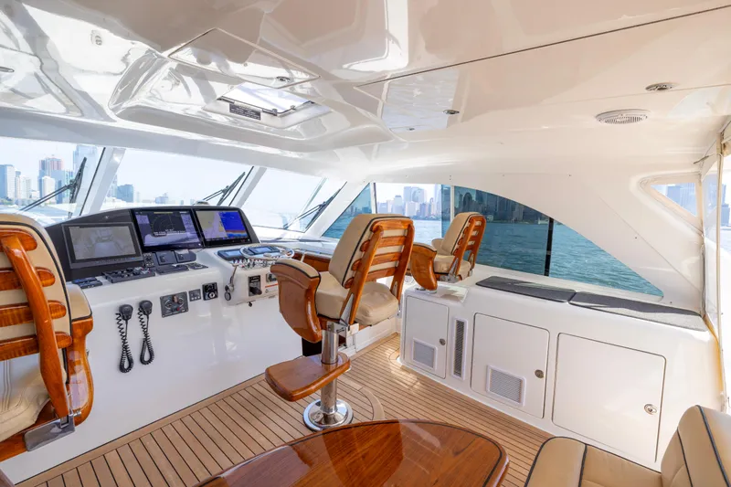  Yacht Photos Pics Luxurious 2012 Cabo 44 Hardtop Express yacht interior with helm, wooden seats, and city skyline view.