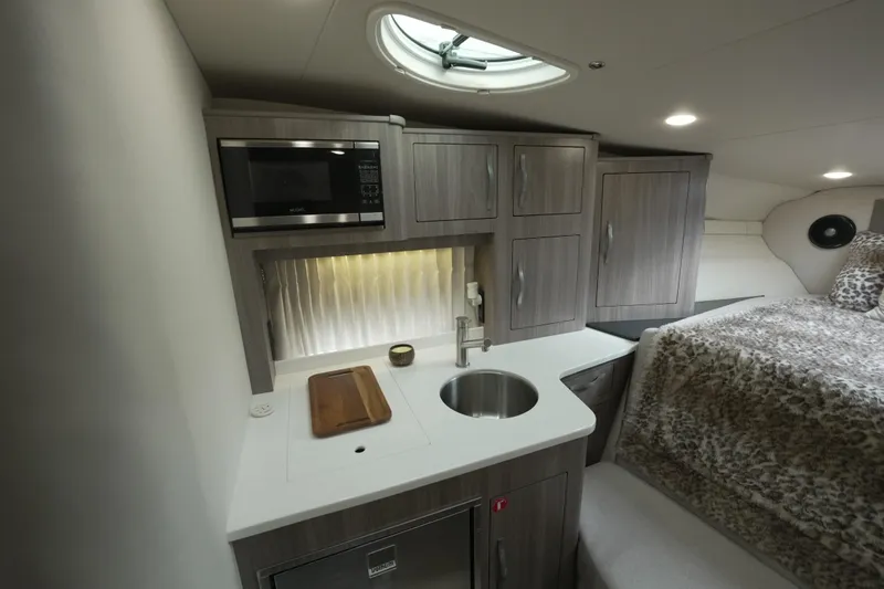  Yacht Photos Pics 2021 Regal 33 XO yacht interior with kitchenette, microwave, sink, and cozy sleeping area.