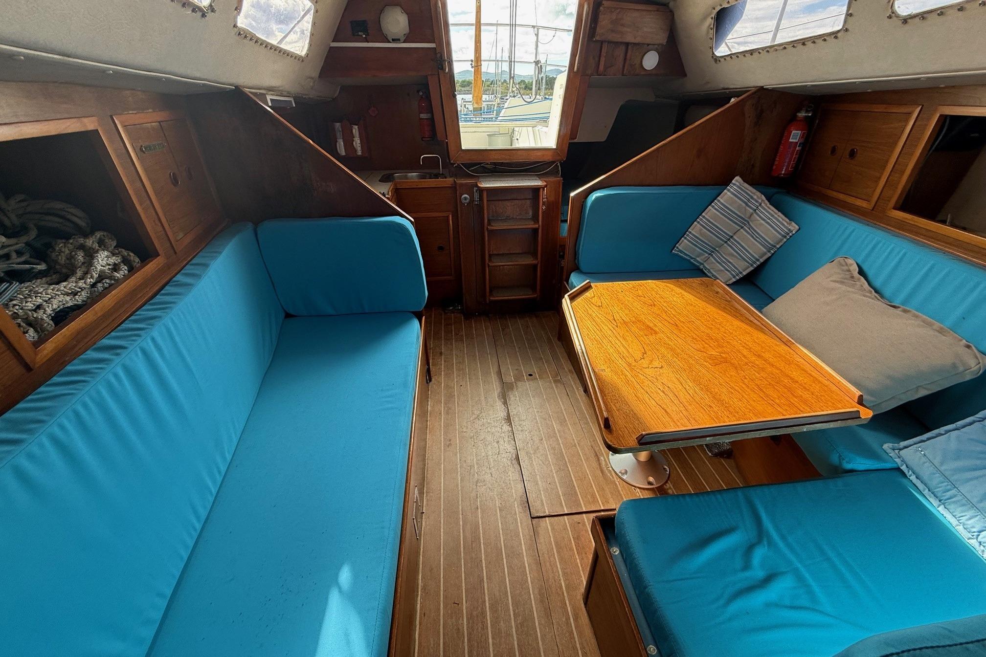 1984 Trapper T30 yacht interior with blue seating, wooden table, and nautical decor.