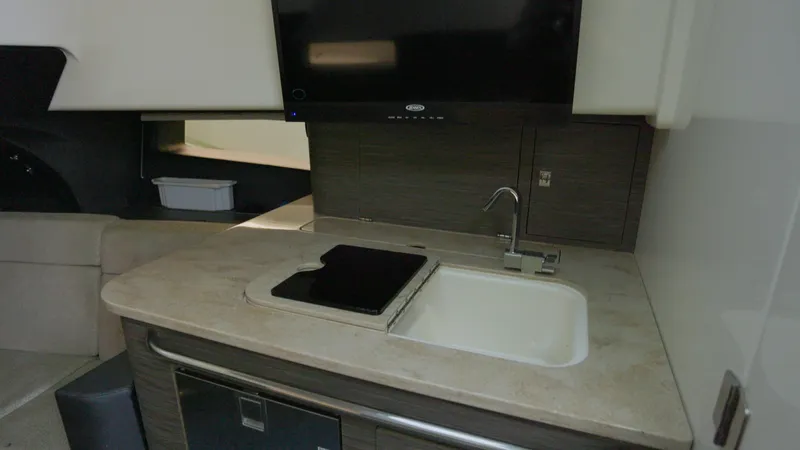  Yacht Photos Pics 2016 Boston Whaler 420 Outrage kitchen area with sink, stove, and TV.