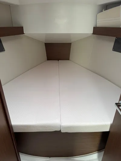 Xanadu Yacht Photos Pics 2024 Beneteau Oceanis 34.1 cabin interior with cozy white bedding and wooden accents.