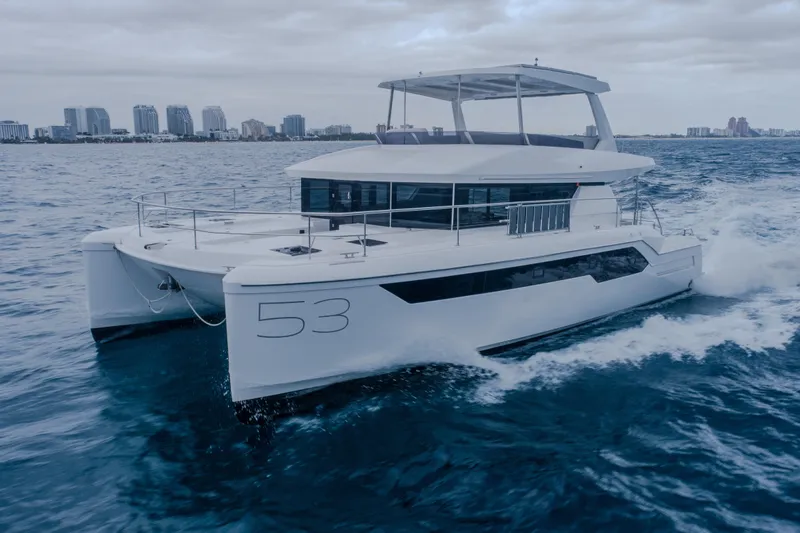 Althea Yacht Photos Pics 2025 Leopard 53 Powercat cruising on ocean near city skyline.