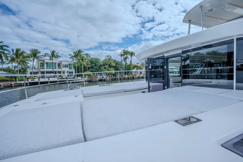 Althea Yacht Photos Pics 2025 Leopard 53 Powercat yacht with spacious deck, docked near waterfront homes.