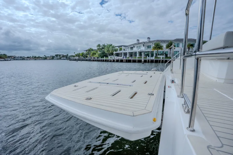 Althea Yacht Photos Pics 2025 Leopard 53 Powercat yacht docked by waterfront homes under cloudy sky.