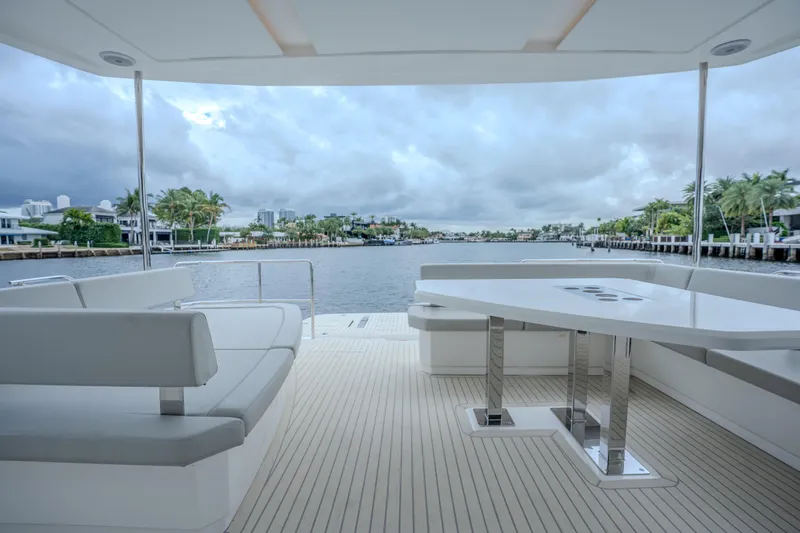 Althea Yacht Photos Pics 2025 Leopard 53 Powercat yacht deck with modern seating and table, overlooking serene waterfront.