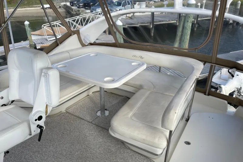  Yacht Photos Pics 2000 Sea Ray 400 Sedan Bridge interior with white seating and table, docked at marina.