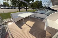2023 Elling E4 yacht deck with seating and table, docked near parked cars and trees.