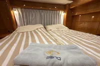 Luxurious 2023 Elling E4 yacht cabin with striped bedding and branded towel.