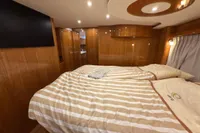 Luxurious cabin interior of 2023 Elling E4 yacht with striped bedding and wood paneling.