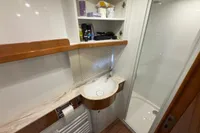 Modern bathroom in 2023 Elling E4 yacht with sink, shower, and storage shelves.