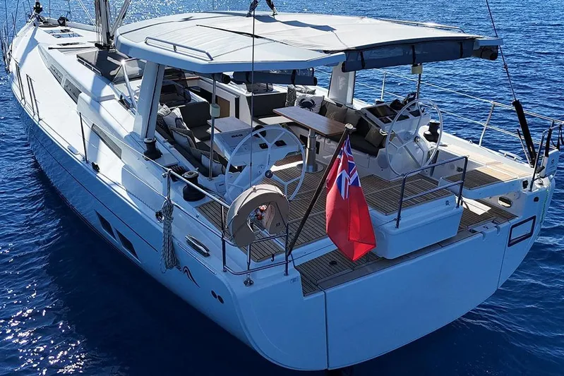 Nil Yacht Photos Pics 2024 Hanse 588 yacht on blue ocean, featuring dual steering wheels and a red flag.