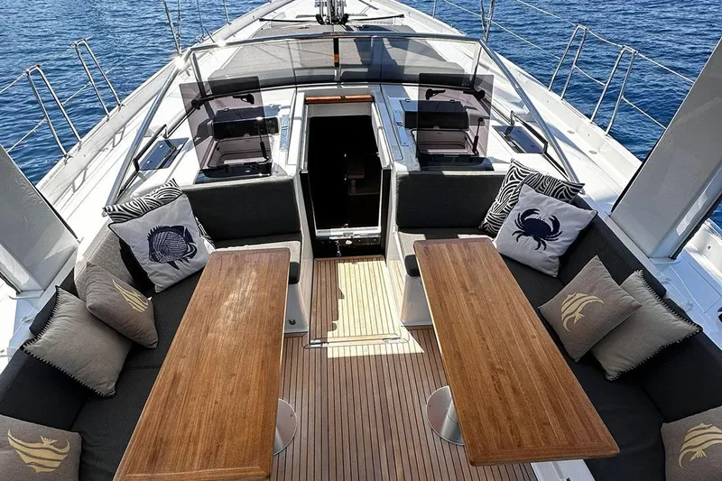 Nil Yacht Photos Pics Luxurious 2024 Hanse 588 yacht deck with elegant seating and wooden tables.