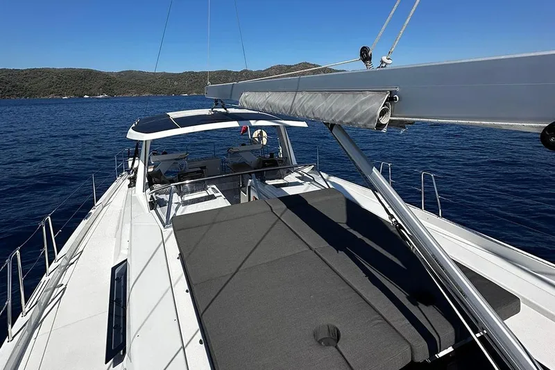 Nil Yacht Photos Pics 2024 Hanse 588 yacht deck with sunbathing area, sailing on calm blue waters.