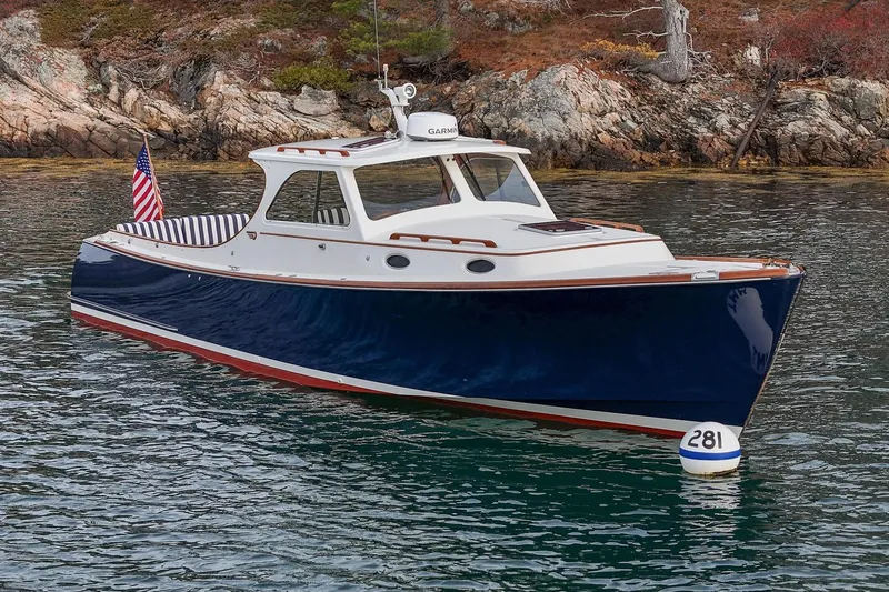 Seaker Yacht Photos Pics 2001 Hinckley Picnic Boat Classic on water, near rocky shoreline.