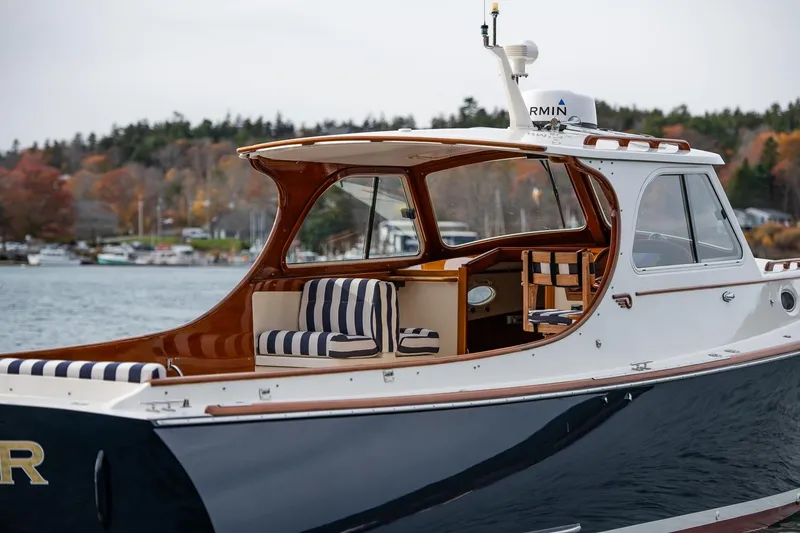 Seaker Yacht Photos Pics 2001 Hinckley Picnic Boat Classic with striped seating, docked by a scenic shoreline.