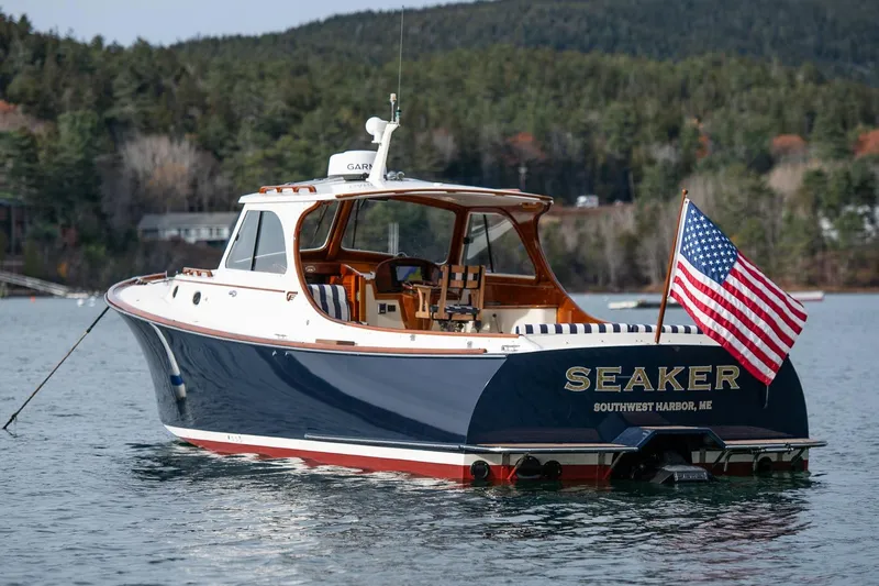 Seaker Yacht Photos Pics 2001 Hinckley Picnic Boat Classic on water, American flag, forested background.