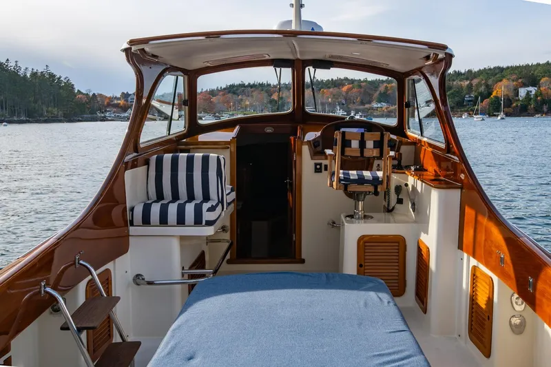 Seaker Yacht Photos Pics 2001 Hinckley Picnic Boat Classic interior with striped seating, overlooking serene waters and autumn foliage.