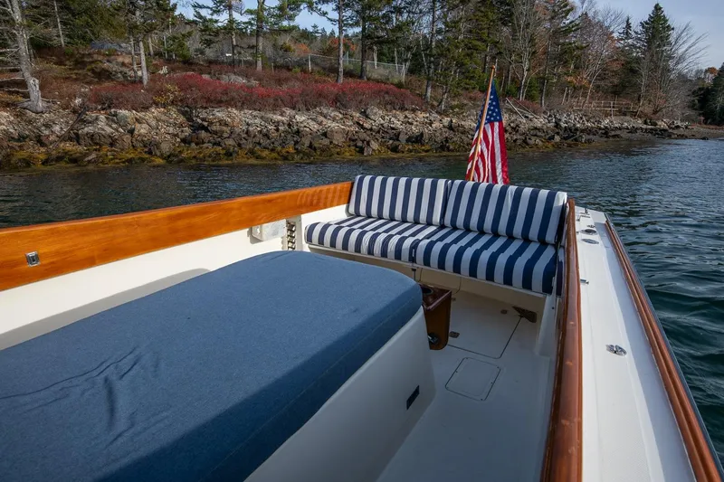 Seaker Yacht Photos Pics 2001 Hinckley Picnic Boat Classic with striped seating, American flag, and scenic shoreline view.