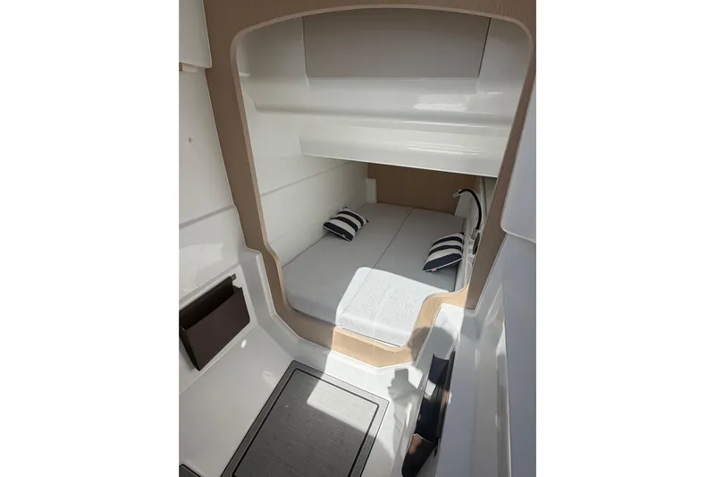  Yacht Photos Pics 2026 Jeanneau TH33 cabin interior with cozy bed and striped pillows.