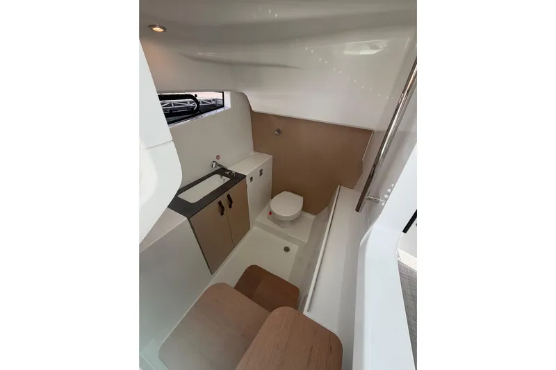  Yacht Photos Pics Modern bathroom interior of 2026 Jeanneau TH33 boat, featuring sink, toilet, and storage.