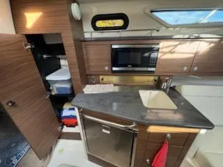  Yacht Photos Pics 2023 Boston Whaler 325 Conquest kitchen with modern appliances and wood cabinetry.