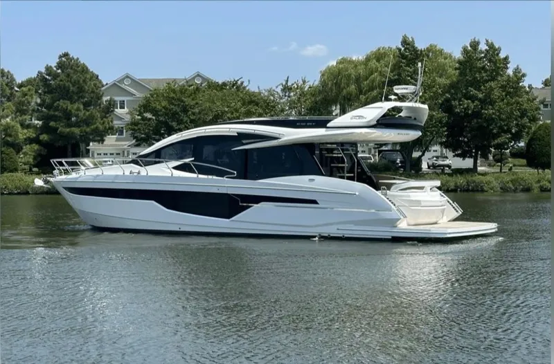 The Good Life Yacht Photos Pics 2024 Galeon 510 Sky yacht on calm water near houses.