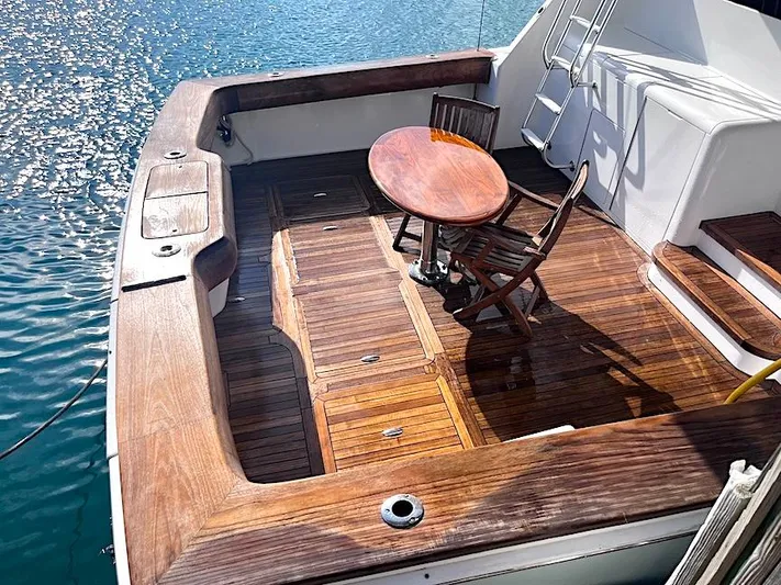  Yacht Photos Pics 1999 Viking Boats Convertible with wooden deck, table, and chairs on calm water.