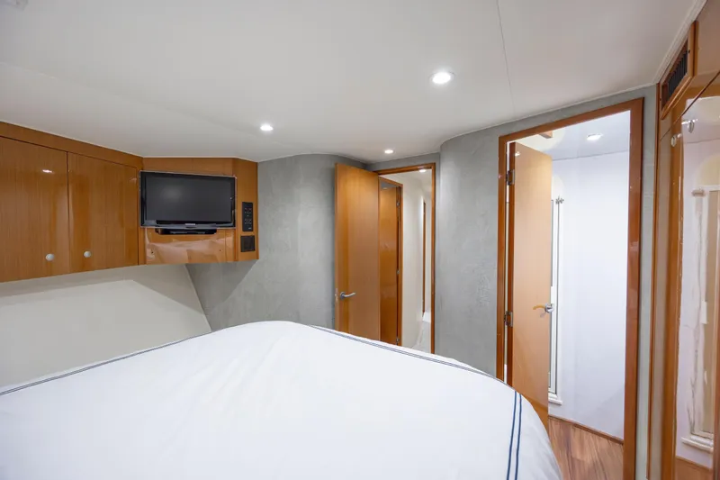Emeritus Yacht Photos Pics Interior of 2001 Viking 61 Convertible yacht bedroom with TV and wooden cabinetry.