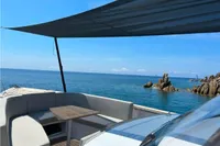2023 Fjord 38 Open yacht with canopy, overlooking serene ocean and rocky coastline.