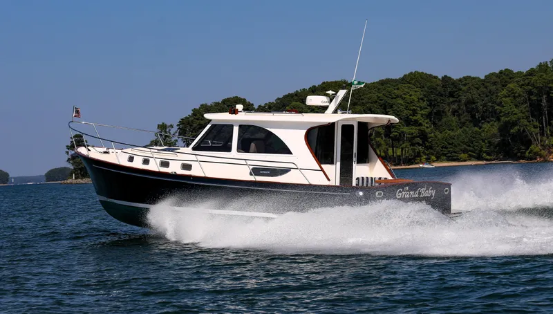 Grand Baby Yacht Photos Pics Legacy 42 boat cruising on a lake, 2018 model, with lush green trees in the background.