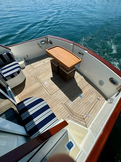 Grand Baby Yacht Photos Pics Legacy 42 boat deck, 2018 model, with striped seating and wooden table on calm water.
