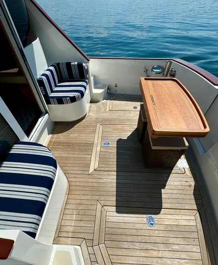 Grand Baby Yacht Photos Pics Luxury yacht deck with striped seating, wooden table, and ocean view. Legacy 42, 2018 model.
