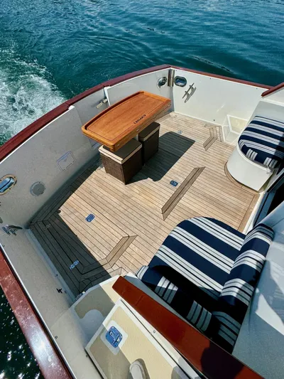 Grand Baby Yacht Photos Pics Legacy 42 boat deck, 2018 model, with striped seating and wooden table on calm water.