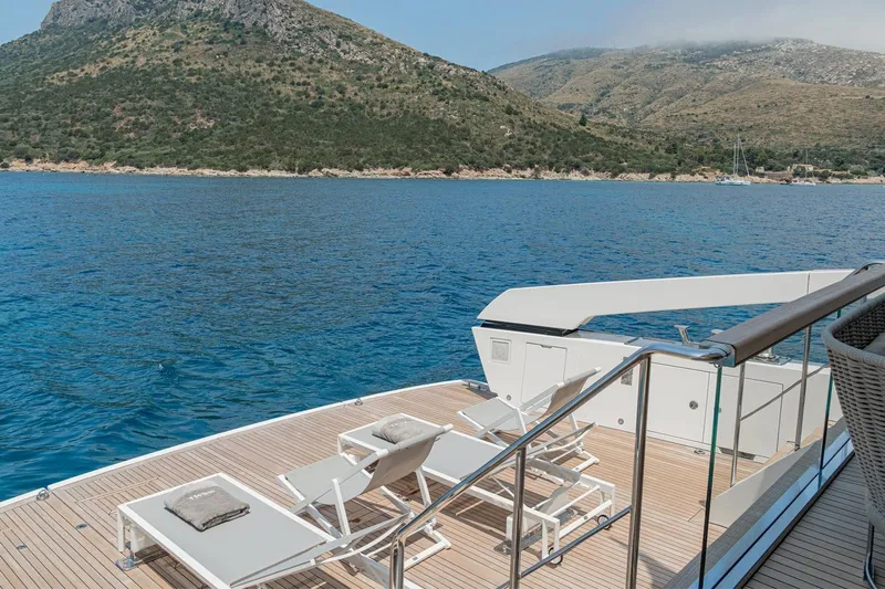 4leon Yacht Photos Pics Luxurious Navetta 33 yacht deck with sun loungers, overlooking serene blue waters and scenic hills.