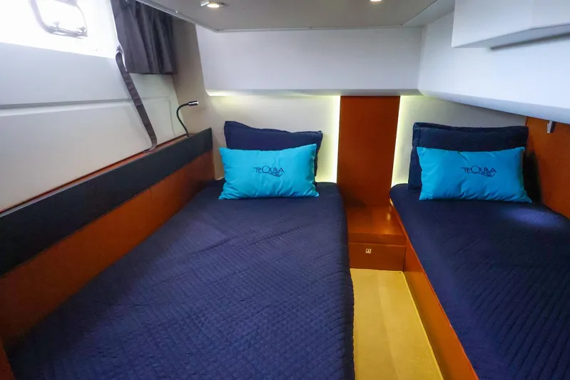 Tequila Little Time II Yacht Photos Pics 2015 Jeanneau NC 14 cabin with twin beds, blue bedding, and teal pillows.