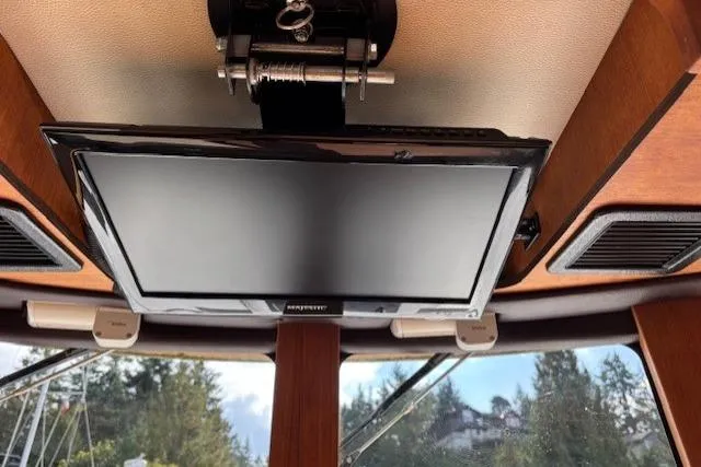 Fish Tank Yacht Photos Pics Ceiling-mounted TV inside 2013 Ranger Tugs R-31 boat, with wooden interior and outdoor view.
