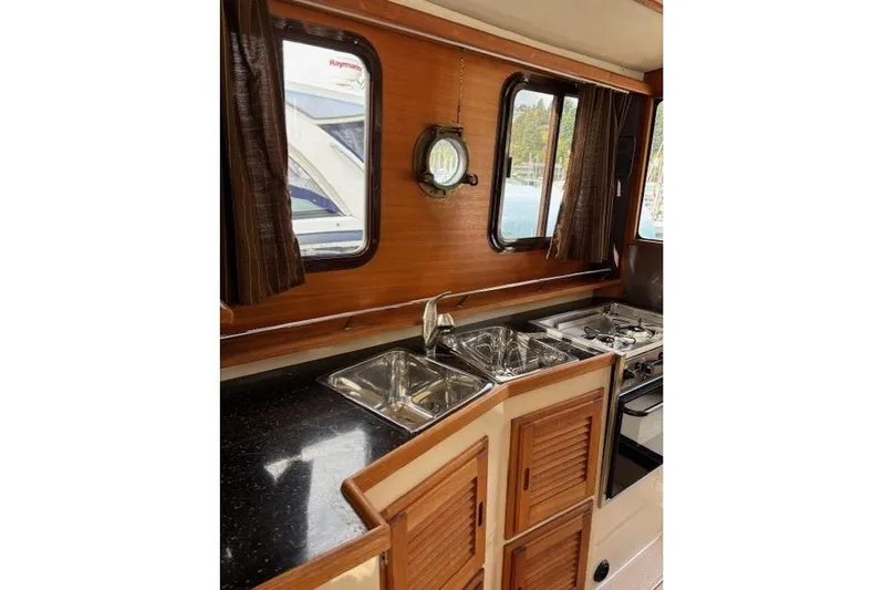 Fish Tank Yacht Photos Pics 2013 Ranger Tugs R-31 interior kitchen with wooden cabinets, stainless steel sink, and stove.