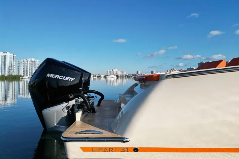  Yacht Photos Pics 2026 Lilybaeum Lipari 31 boat with Mercury engine on calm water, city skyline in background.
