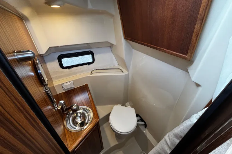  Yacht Photos Pics 2026 Ranger Tugs R-25 boat bathroom with sink, toilet, and wooden cabinetry.